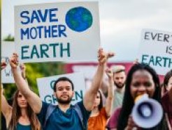 Demonstrierende mit einem Megaphon und einem Plakat "Save Mother Earth"