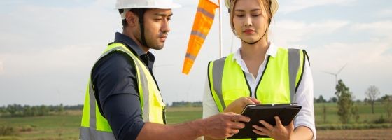 Menschen vor Windrädern mit einem Laptop