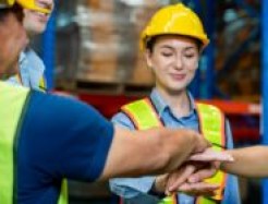 Arbeiter*innen in Warnwesten legen ihre Hände übereinander