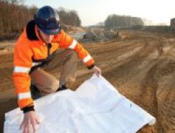 Mensch in Warnkleidung mit Planungsskizzen