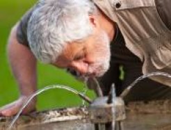 älterer Mann am Trinken aus Wasserspender