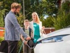 Familie steht um ihr E-Auto herum 