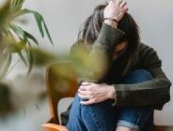 Person sitzt zusammengekauert und sieht leidend aus